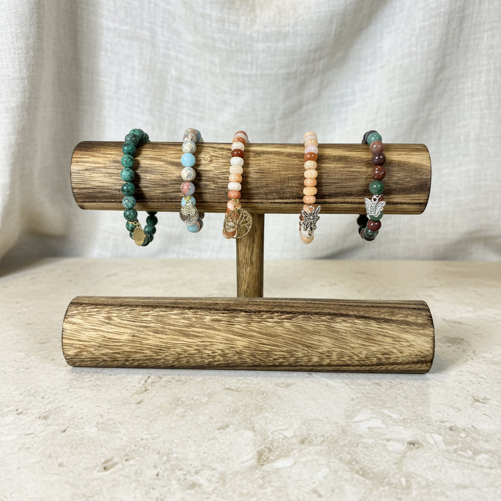 Wooden bracelet holder with beaded bracelets against a white wall.