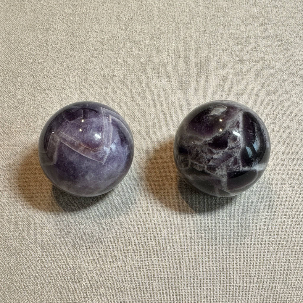 Two marbled purple and gray spheres on a white surface