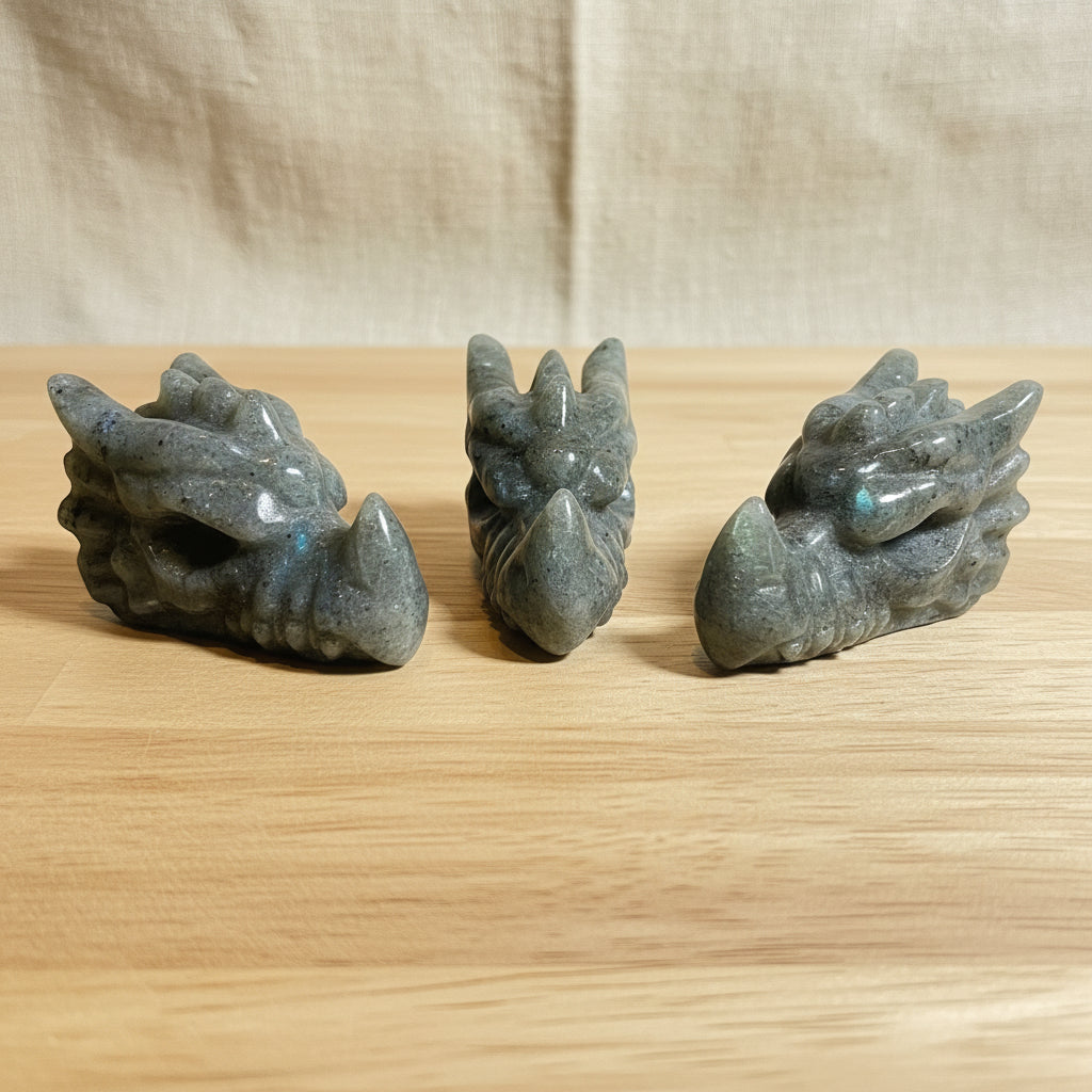 Three stone carvings of dragon heads on a wood background