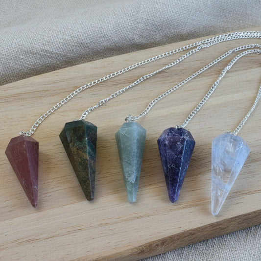 Five crystal pendulums on a wooden surface