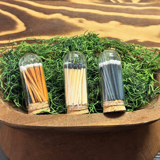Three glass containers with matches on a wooden stand with grass