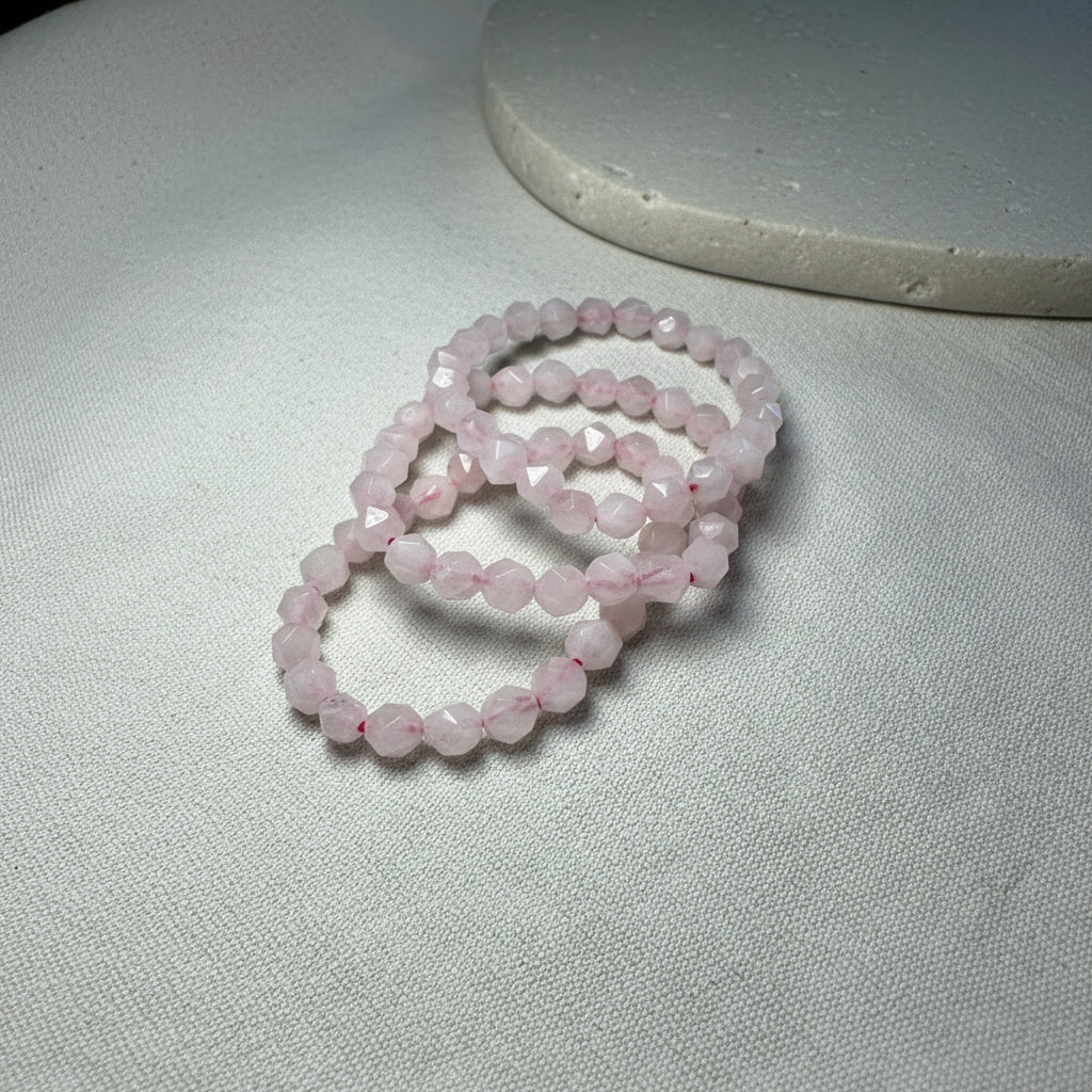 Three pink beaded bracelets on a neutral surface