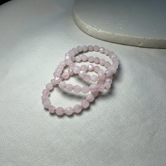 Three pink beaded bracelets on a neutral surface