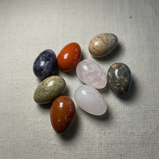 Assorted colorful stone eggs on a fabric surface
