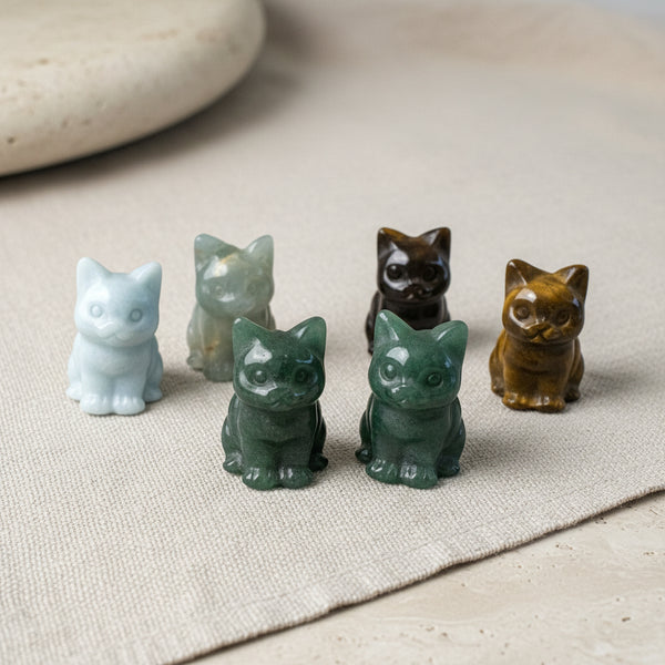 Set of five crystal cat figurines on a neutral surface
