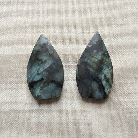 two flame shaped gemstones on tan surface