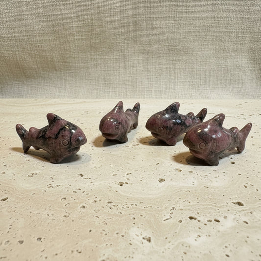 Five small shark figurines on a white surface