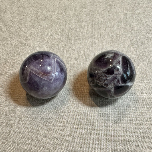 Two marbled purple and gray spheres on a white surface
