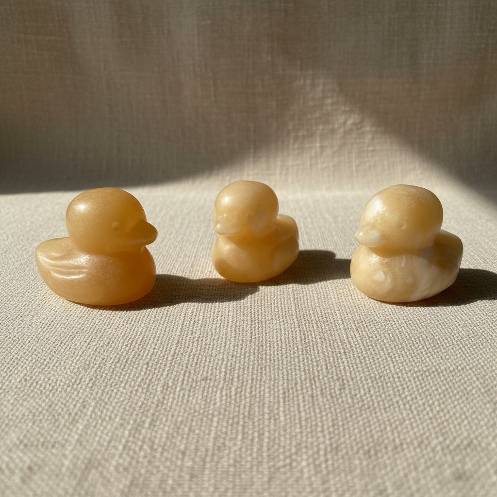 Three small stone duck sculptures on a white background