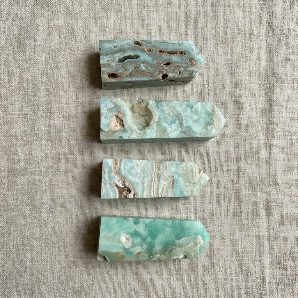 Four pieces of green and brown stone on a light gray fabric