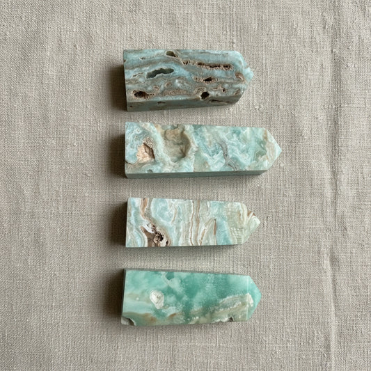 Four pieces of green and brown stone on a light gray fabric