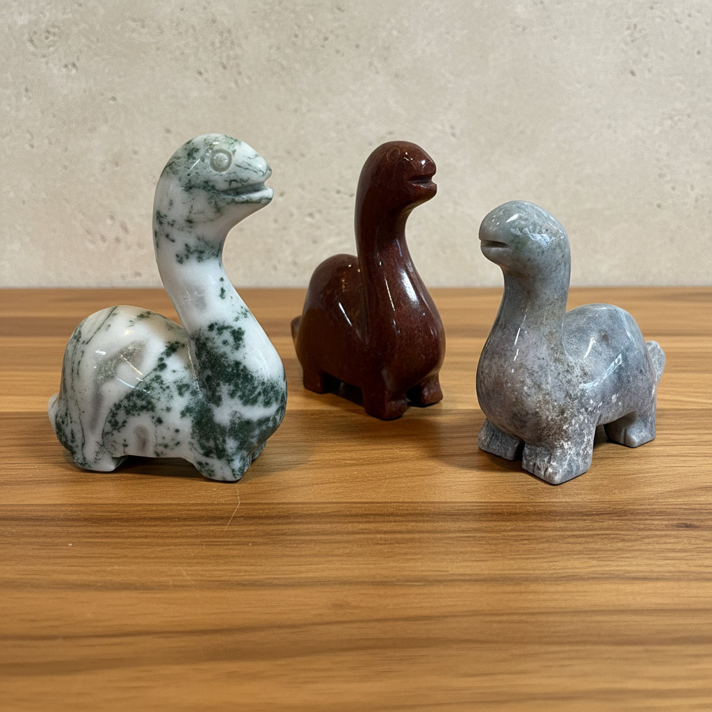Three stone sculptures of stylized animals on a wood surface