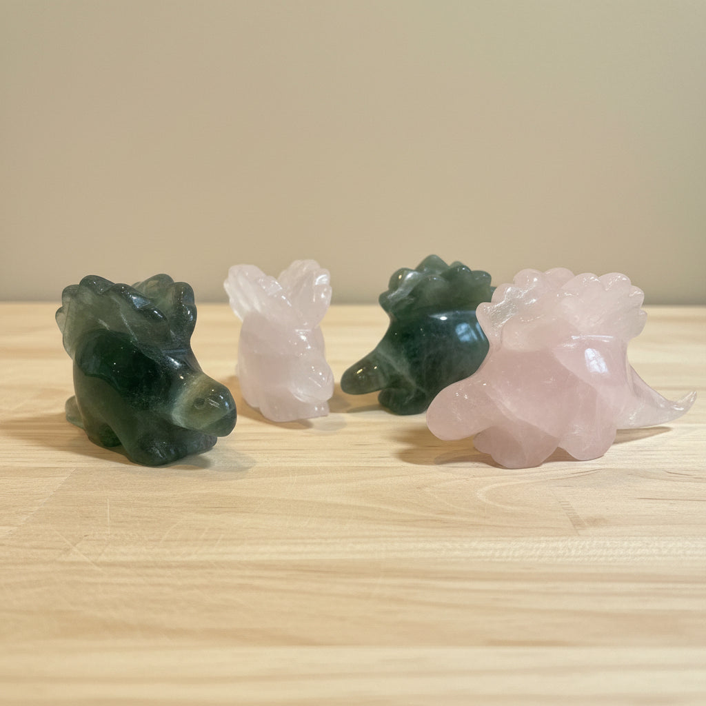 Four crystal dinosaur figurines on a wood surface
