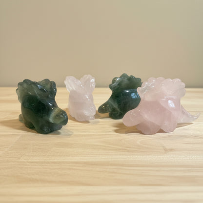 Four crystal dinosaur figurines on a wood surface