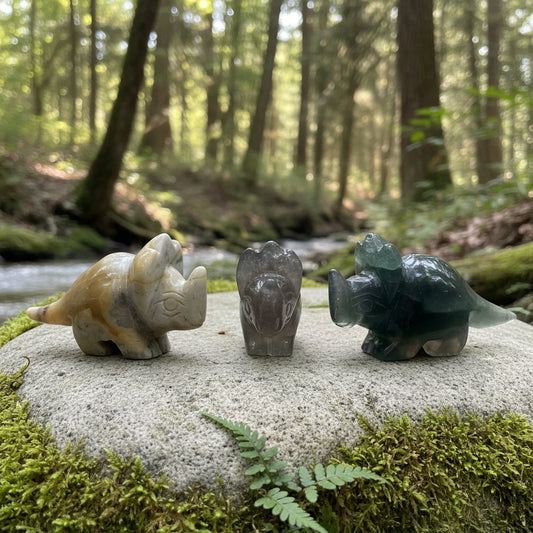 Three stone carvings of dinosaurs on a forest background

